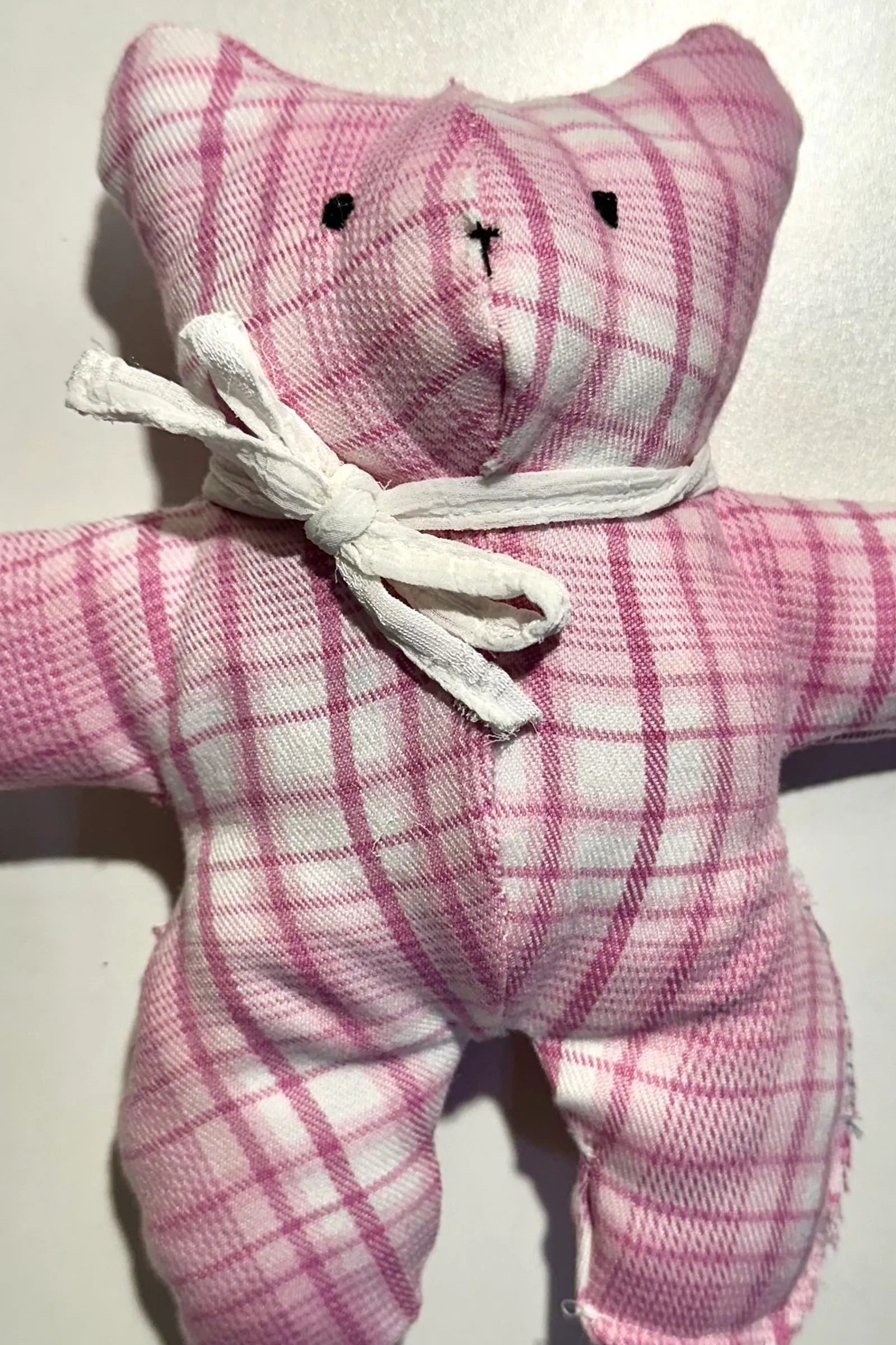 A handmade pink plaid bear, one of the plushies students sew by hand
